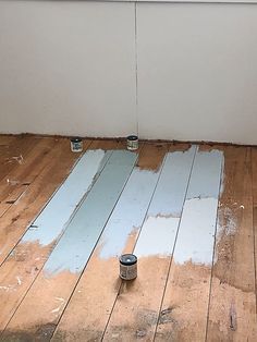 two paint cans are sitting on the floor next to a wall that has been stripped off