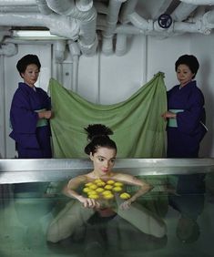 two women in scrubs are holding lemons and looking at the camera while another woman stands behind them