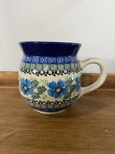 a blue and white flowered vase sitting on top of a wooden table next to a wall