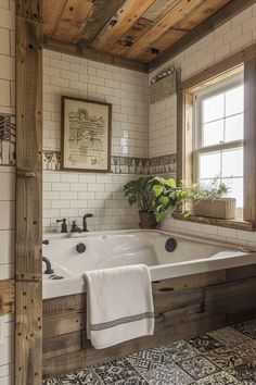 a bathroom with a large white bath tub next to a window filled with potted plants