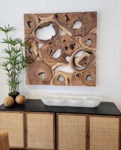 an art piece is displayed on the wall next to a bamboo plant and some wicker baskets