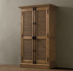 a tall wooden cabinet with shutters on the front and side doors, against a gray wall