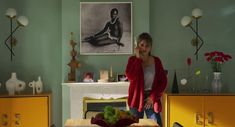 a woman standing in a living room next to a table with fruit on top of it