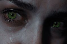 the eyes of a person with green eyes and dark hair are seen in this image