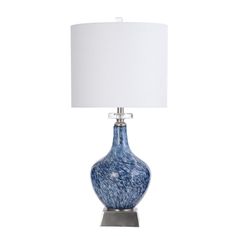 a blue glass lamp with a white shade on the base and a silver metal base