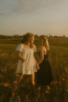 two young women are walking through a field