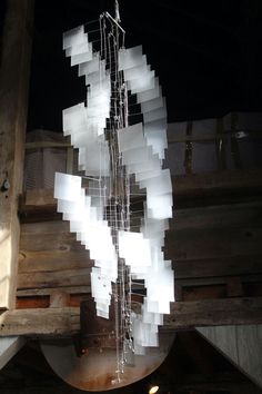 a large white sculpture hanging from the side of a wooden structure in a dark room