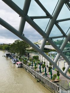 boats are parked on the side of a river under an overhanging metal structure