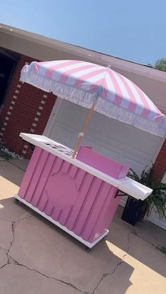 a pink and white ice cream stand with an umbrella