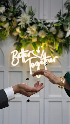 two people reaching out their hands to each other in front of a sign that says better together