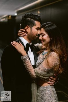 a man in a tuxedo hugging a woman wearing a sequined dress