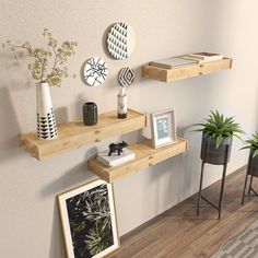 three wooden shelves on the wall with pictures and plants in vases next to them