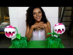 a woman sitting at a table with two paper monsters on top of it and one is holding her hands out