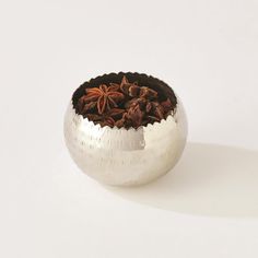 a silver bowl filled with spices on top of a white table