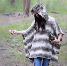 a woman in a hooded ponchy walking through the woods