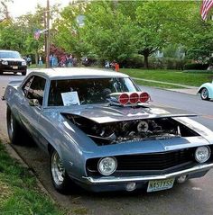 an old muscle car is parked on the side of the road with its hood open