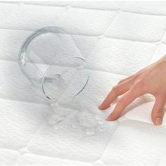 a person's hand on top of a mattress with water in the bottom corner