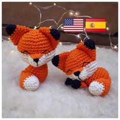 two crocheted stuffed animals sitting next to each other in front of a flag