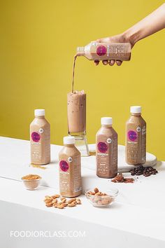 a person is pouring some kind of drink into several bottles on a table with nuts