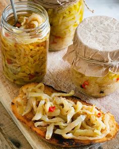 some food is sitting on a cutting board next to two jars and a spoon in it