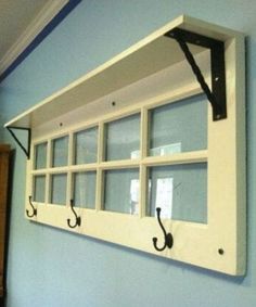 an old window is hung on the wall with black hooks and two coats of coat hangers