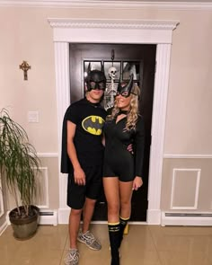 a man and woman dressed up as batman and catwoman posing for a photo in front of a door