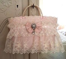 a pink purse hanging on the side of a door with pearls and lace around it