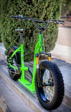 a bright green bike parked on the side of a road next to a bush and sidewalk