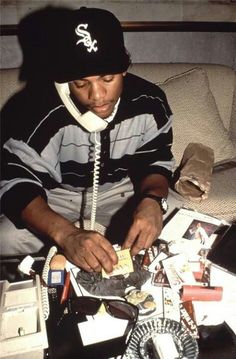 a man sitting on top of a couch holding a phone to his ear while surrounded by assorted items