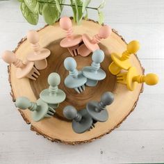 several different colored plastic hair clips sitting on top of a wooden table next to a plant