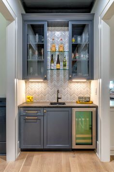 a kitchen with wooden floors and gray cabinets, glass shelves above the stove top oven