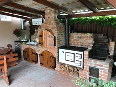 an outdoor kitchen with brick walls and wood stoves on the outside, surrounded by greenery