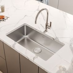 a stainless steel kitchen sink on a marble countertop