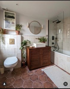 a bathroom with a sink, toilet and bathtub next to a shower stall filled with plants