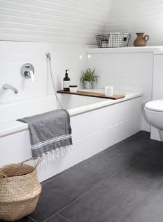 a white bathroom with black tile flooring and walls