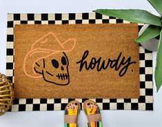 a pair of sandals sitting on top of a door mat next to a potted plant