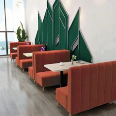 an empty restaurant with red booths and green trees painted on the wall behind them, along with wooden flooring