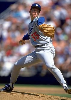 a baseball player pitching a ball on top of a field in front of a crowd