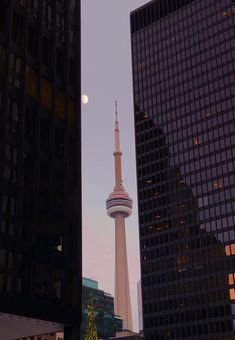 a tall tower towering over a city next to other high rise buildings in the evening