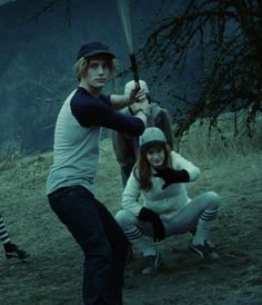 two young people are playing baseball in the dark with one holding a bat while the other holds a stuffed animal