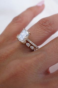 a woman's hand with an engagement ring and diamond band on her left hand