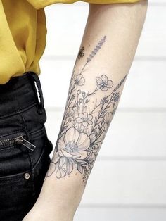 a woman's arm with flowers and a crescent tattoo on the left side of her arm