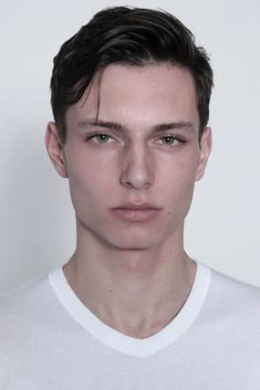 a young man in a white t - shirt looks at the camera with an intense look on his face