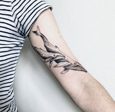 a woman with a whale tattoo on her arm, holding onto the arm of another person's arm