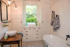 a bath room with a tub a sink and a window on the wall in it