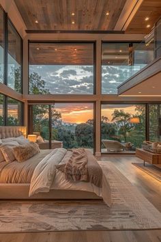 a bedroom with a large bed and lots of windows on the wall, overlooking trees