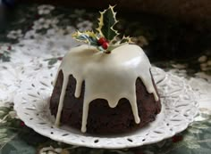 a cake with icing and holly on top sitting on a doily covered table