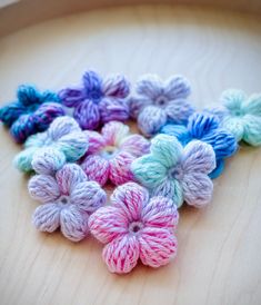 small crocheted flowers sitting on top of a wooden table