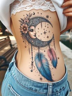 a woman's stomach with a tattoo on it that has a crescent moon and feathers