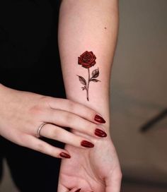 a woman's arm with a rose tattoo on it and two hands holding each other